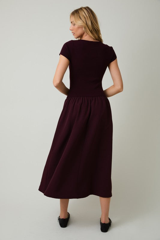 Woman wearing a dark purple dress against a plain background