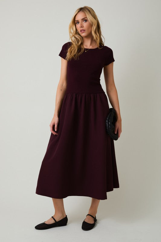 Woman wearing a dark red dress against a plain background