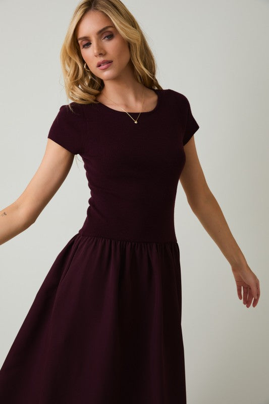 Woman wearing a dark purple dress against a plain background