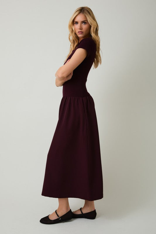 Woman wearing a burgundy dress against a plain background