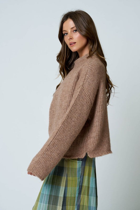 Woman wearing a brown sweater and plaid skirt on a white background