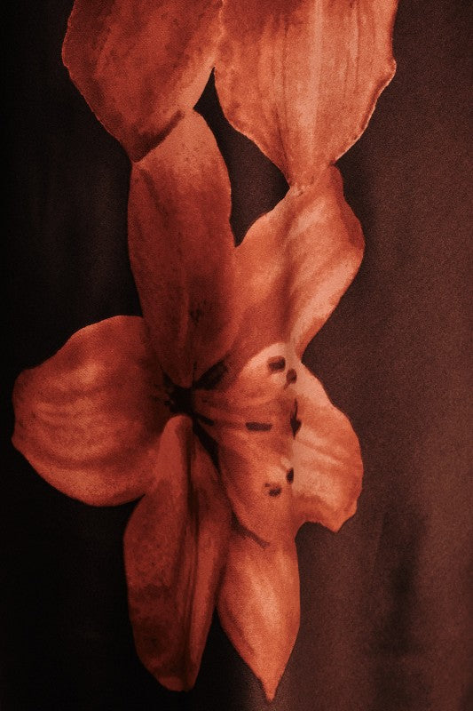 A close-up artistic photograph of a single flower with warm reddish-brown petals against a dark brown background.