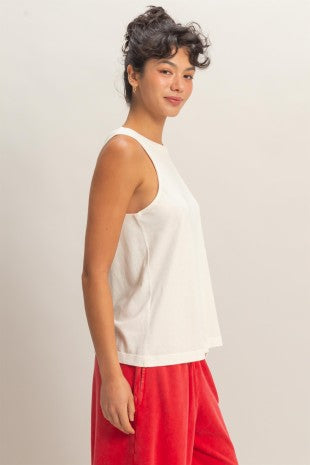 Woman wearing a white sleeveless top and red pants against a plain background