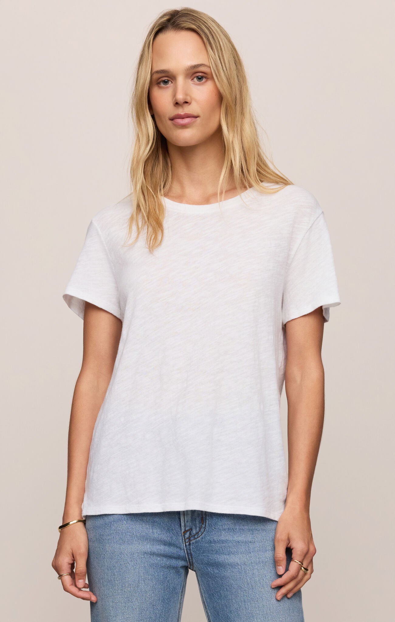 Woman wearing a plain white t-shirt and blue jeans against a beige background