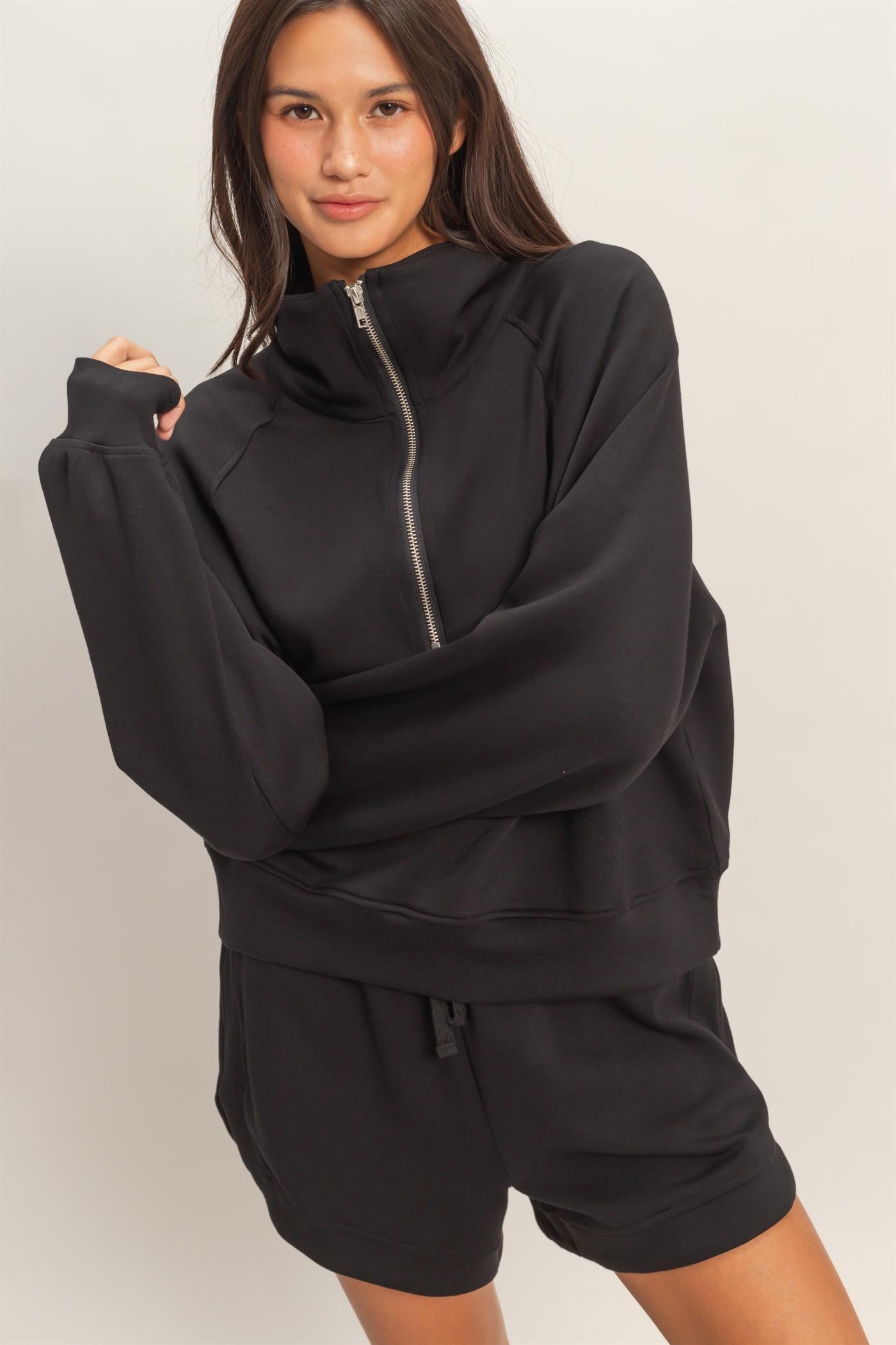 Woman wearing a black tracksuit against a plain background