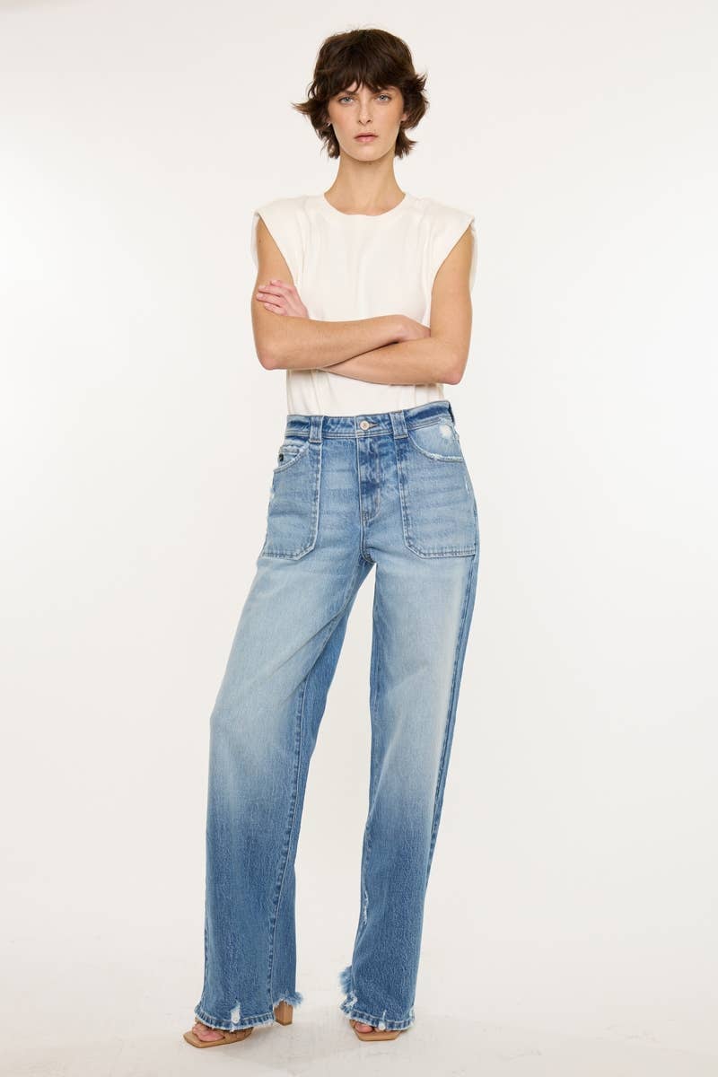Person wearing light blue jeans and a white sleeveless top on a plain background