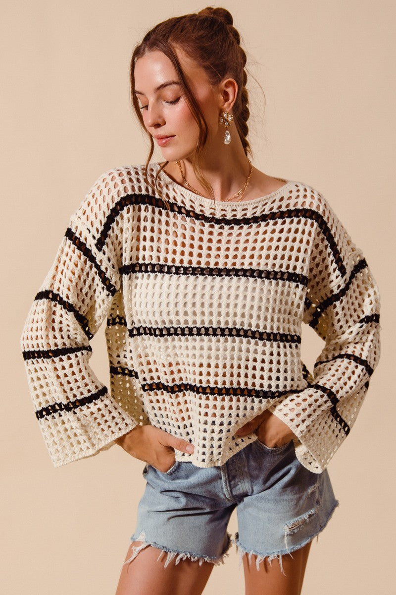 Woman wearing a patterned sweater and denim shorts on a beige background