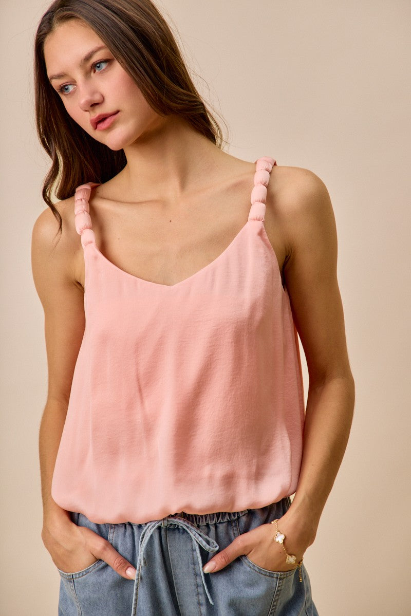 Woman wearing a pink tank top against a beige background
