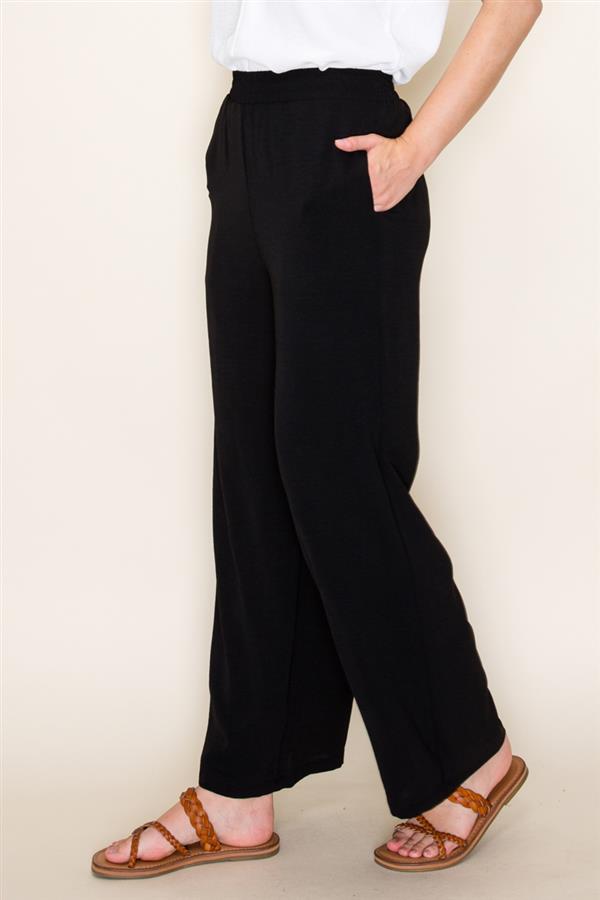 Person wearing black wide-leg pants with a plain background