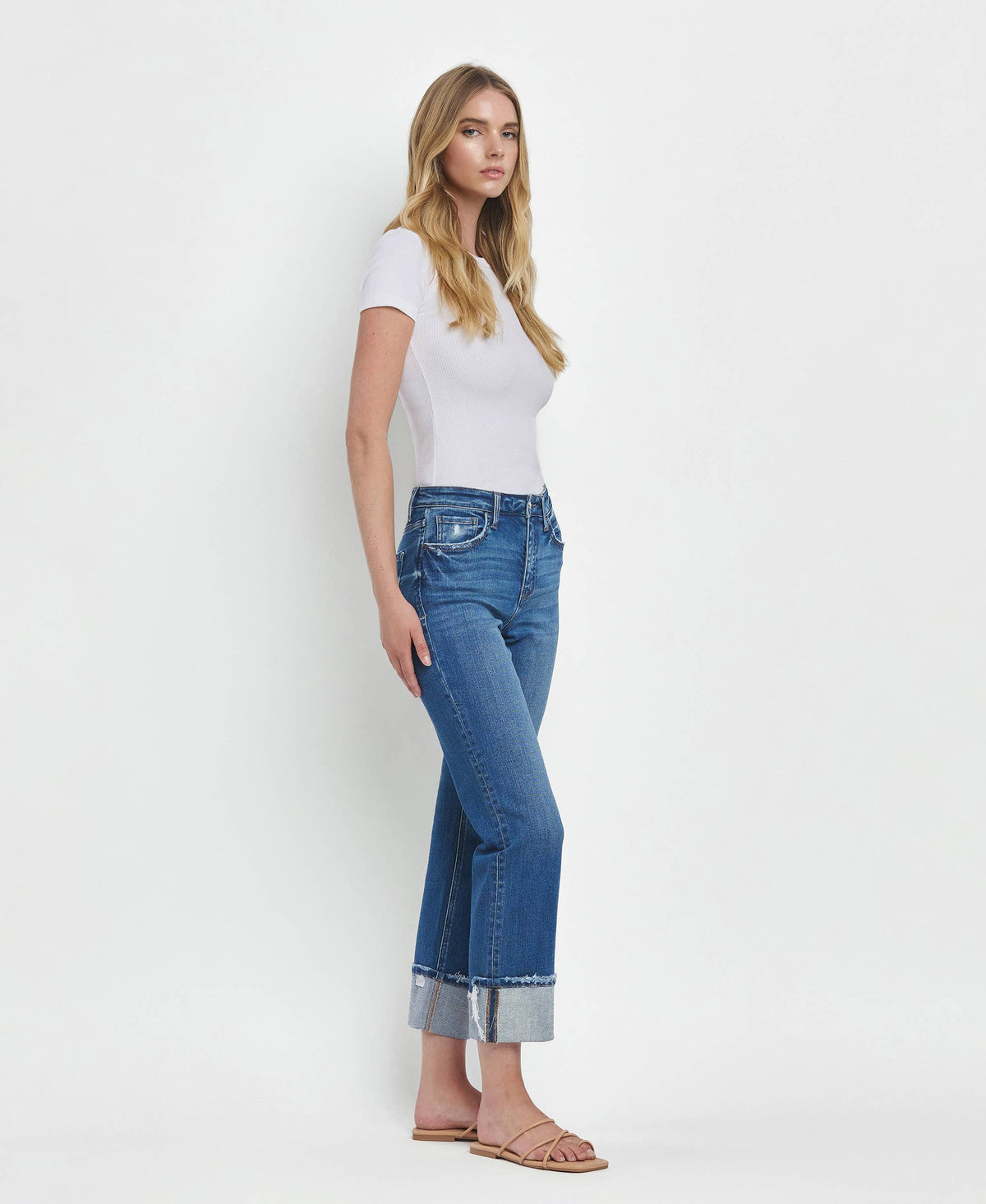 Woman wearing blue jeans and a white top on a white background
