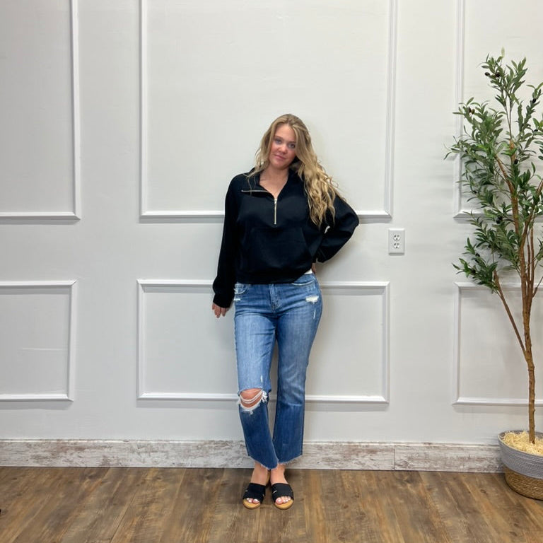 Woman standing in a room with white paneled walls and a plant.