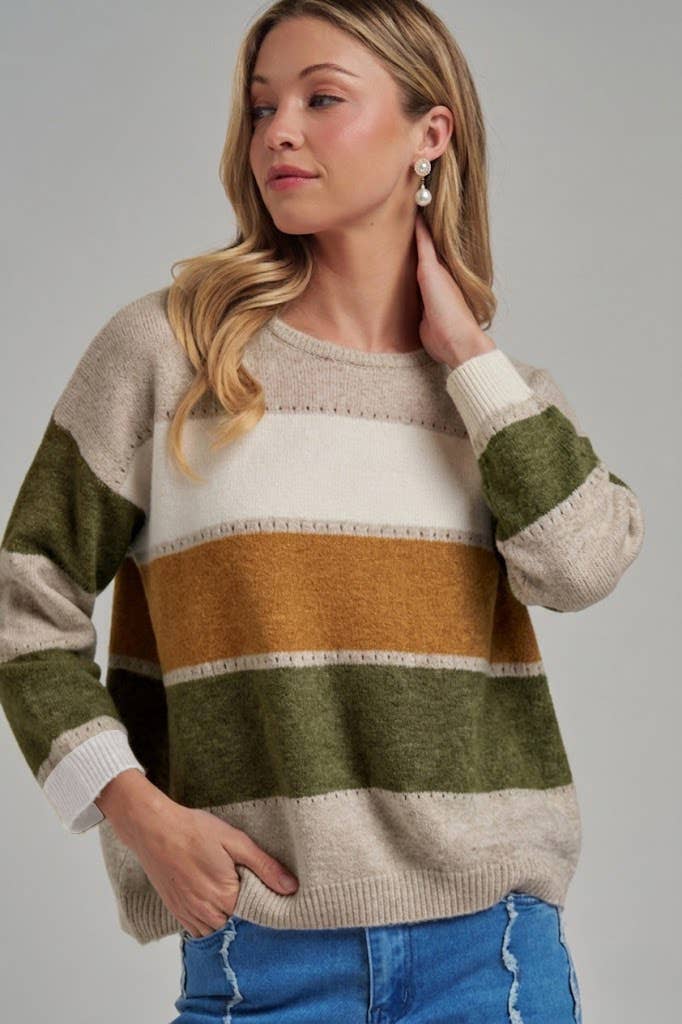 Woman wearing a striped sweater with green, brown, and beige colors on a gray background