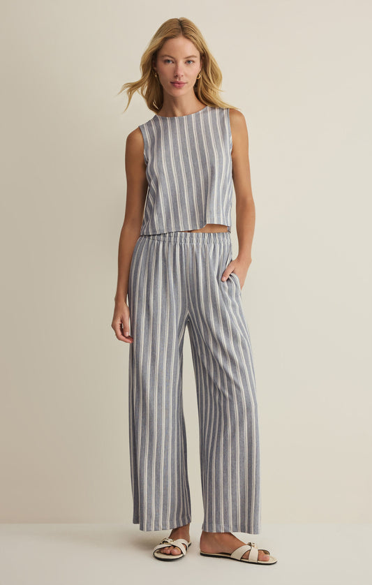 Woman wearing a striped sleeveless top and wide-leg pants on a beige background