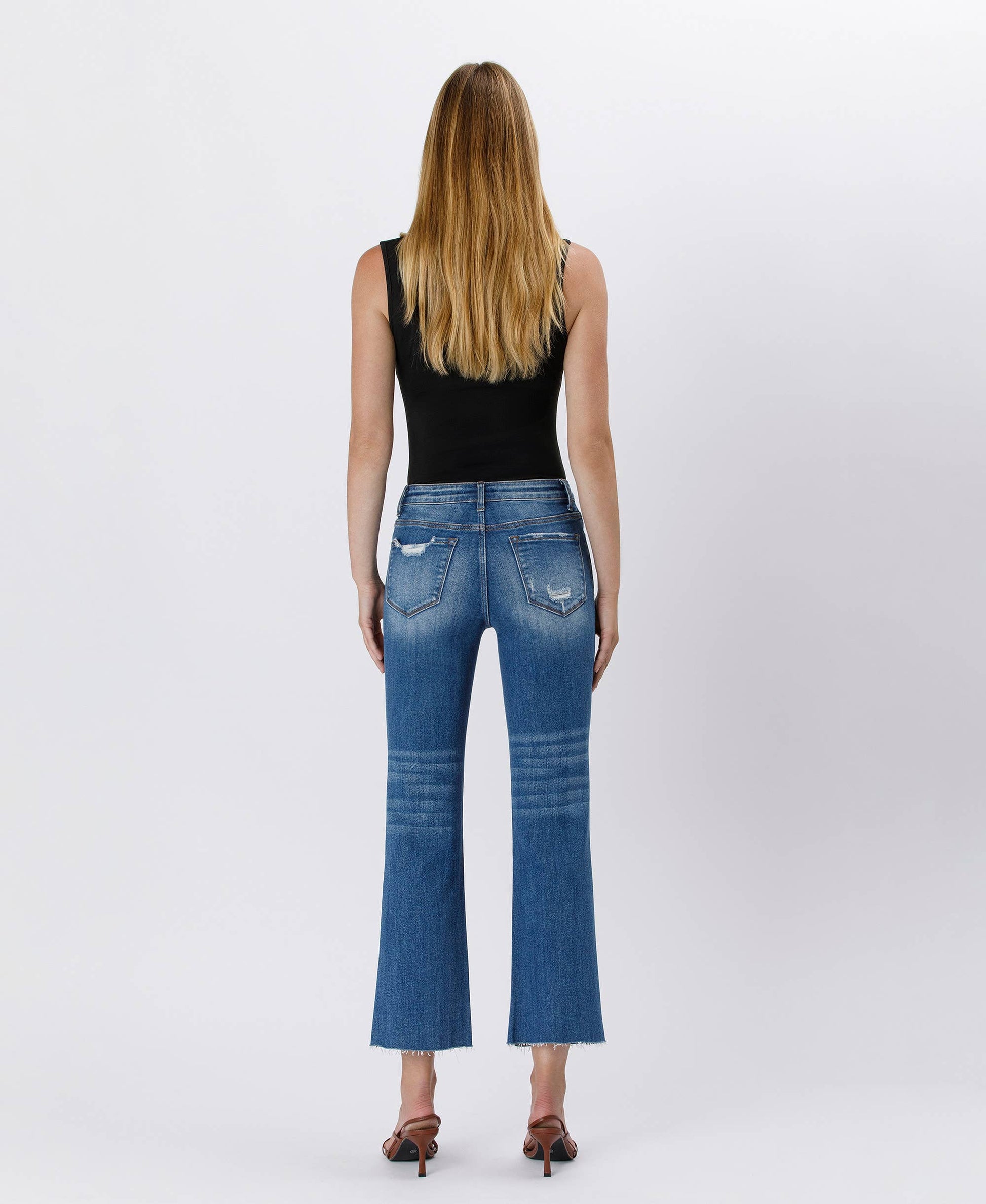 Person wearing blue jeans and a black top on a white background