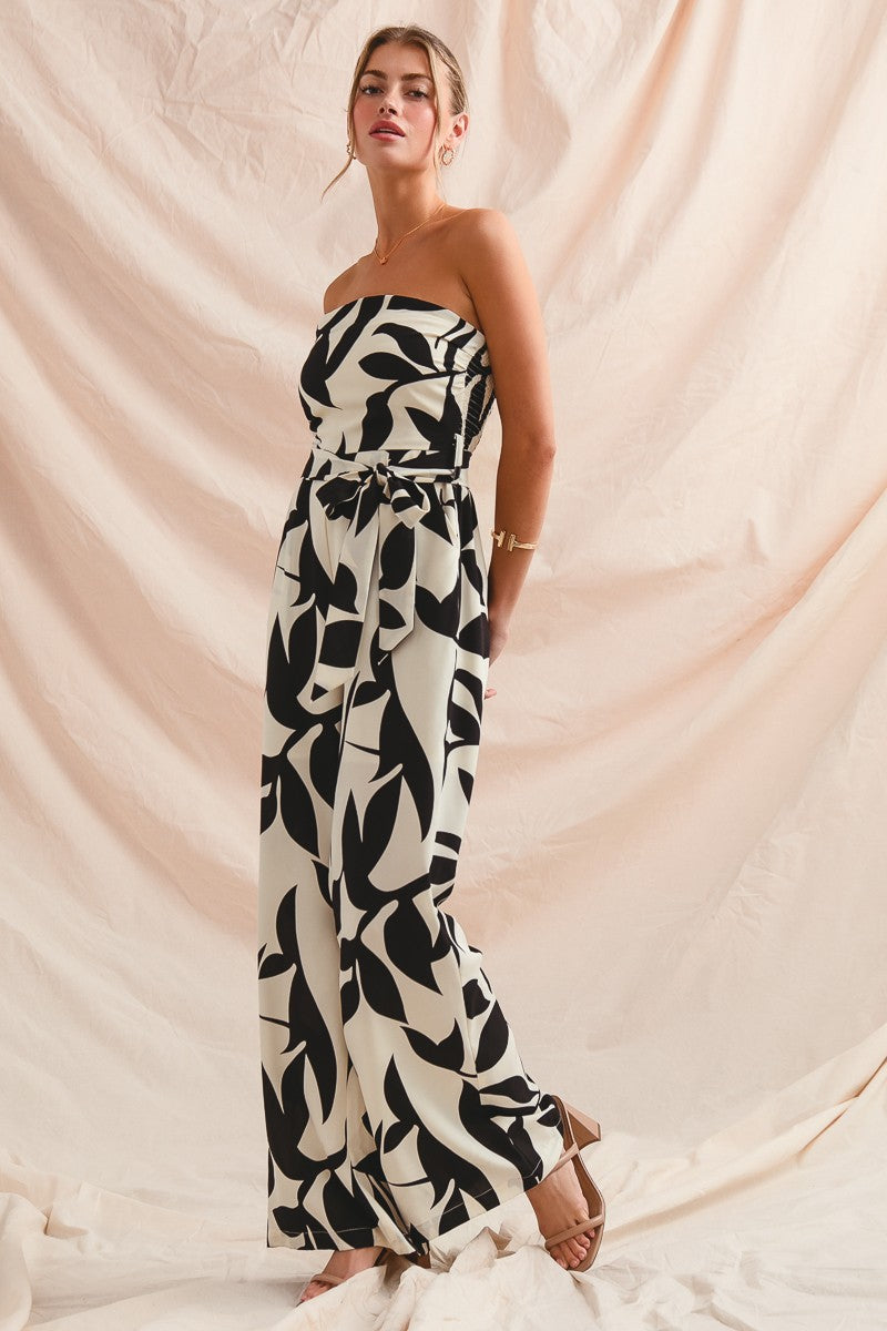 Woman wearing a strapless black and white patterned dress against a beige fabric background