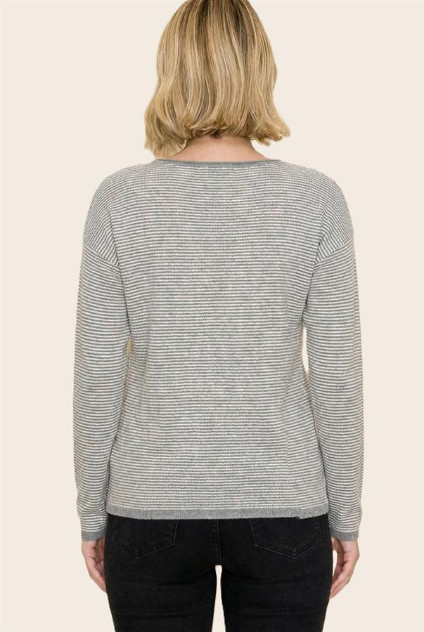 A woman viewed from the back wearing a light gray and white horizontally striped long-sleeve top, paired with black jeans, against a solid light beige background.