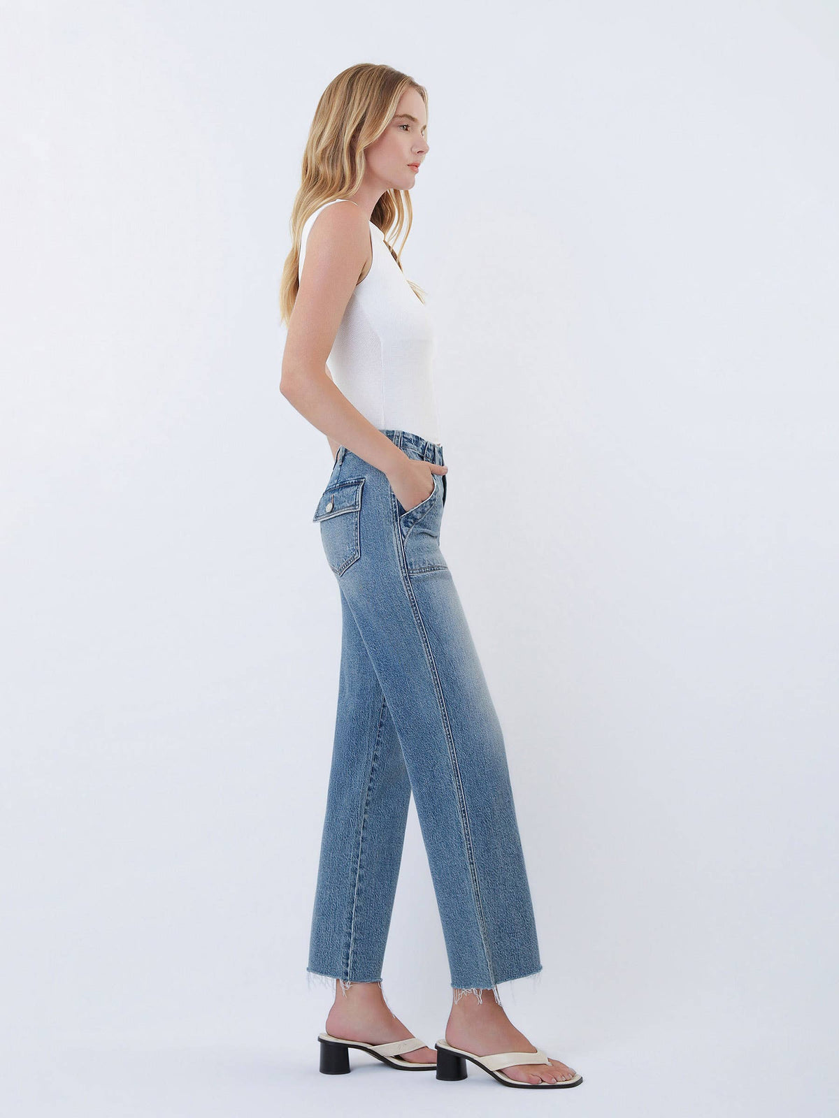 Woman wearing blue jeans and a white top on a white background
