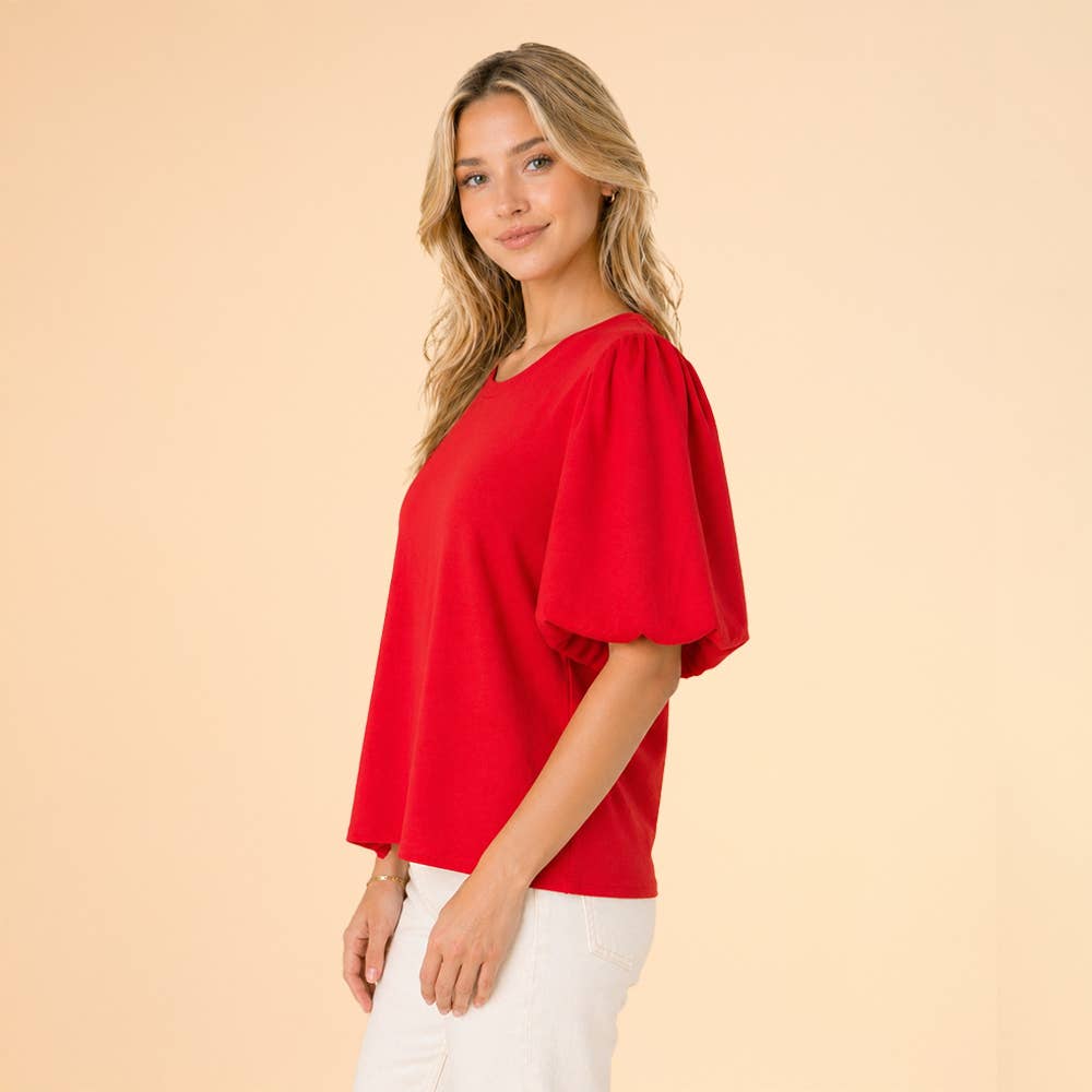 Woman wearing a red blouse against a beige background