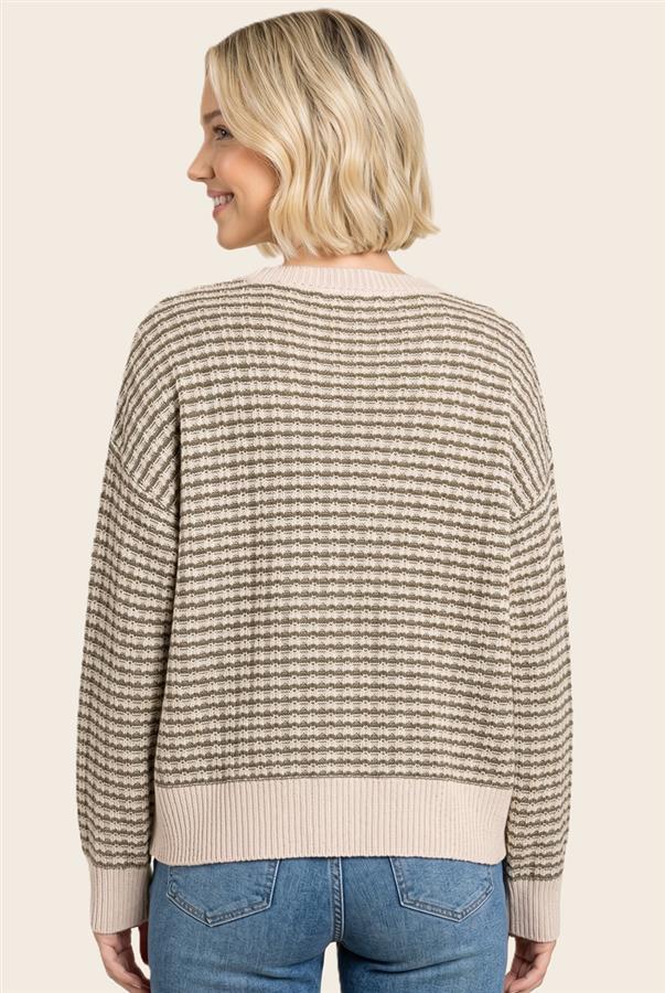 A woman shown from the back wearing a beige and brown horizontally striped knit sweater with ribbed trim, paired with blue jeans, against a solid light beige background.