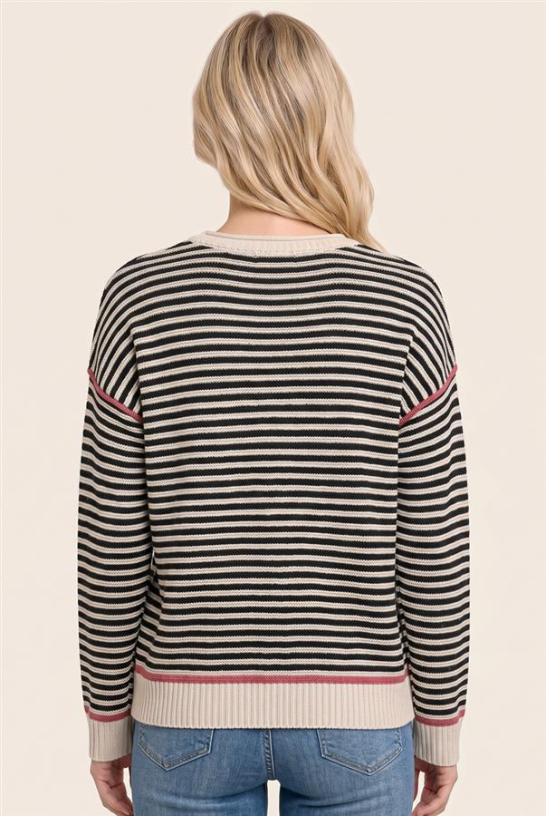 A woman viewed from the back wearing a black and cream striped sweater with thin pink accent stripes, paired with blue jeans, against a solid light beige background.