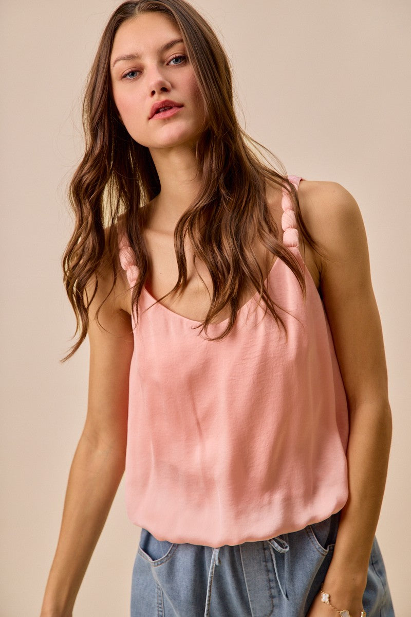 Woman wearing a pink tank top against a beige background