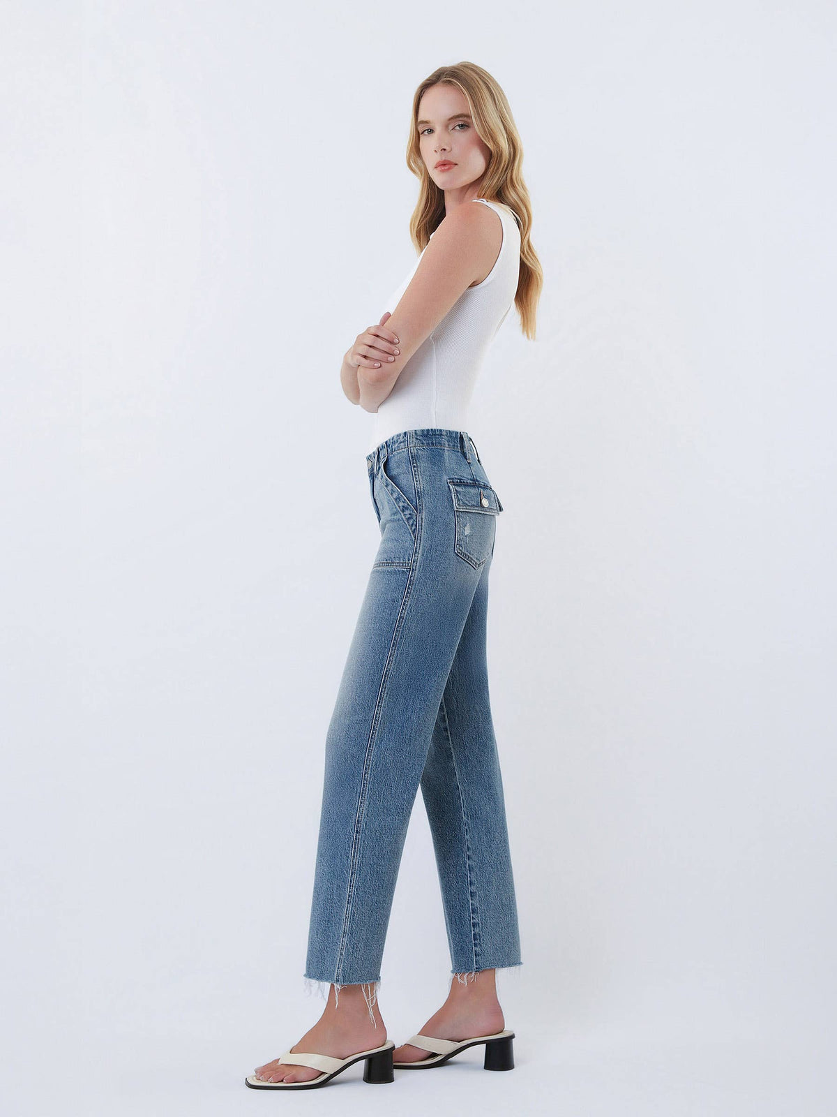 Woman wearing blue jeans and a white top on a white background