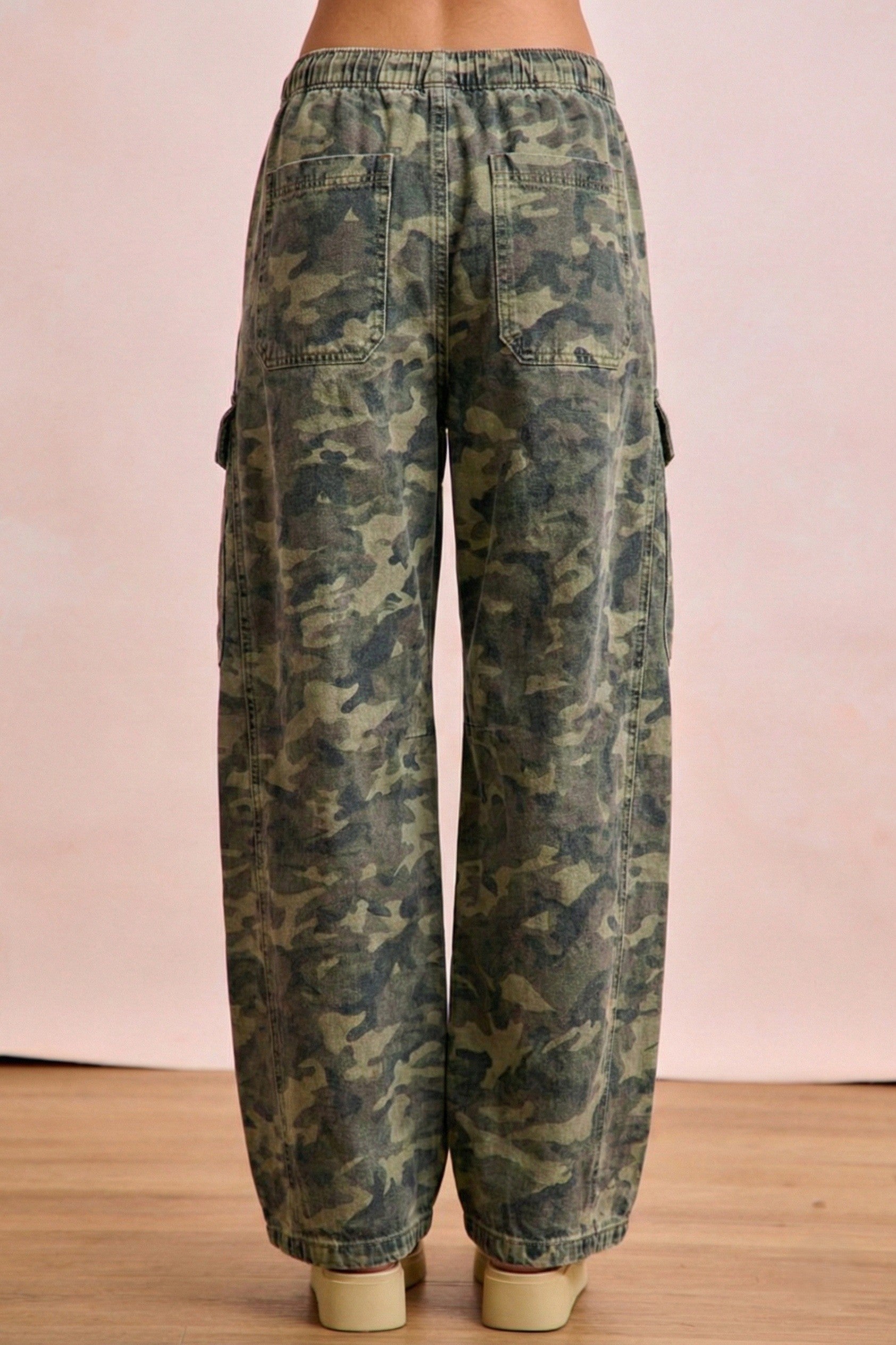 Camouflage pants on a wooden floor with a pink wall background