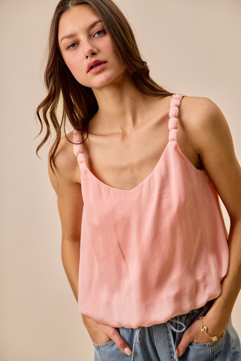 Woman wearing a pink tank top against a beige background