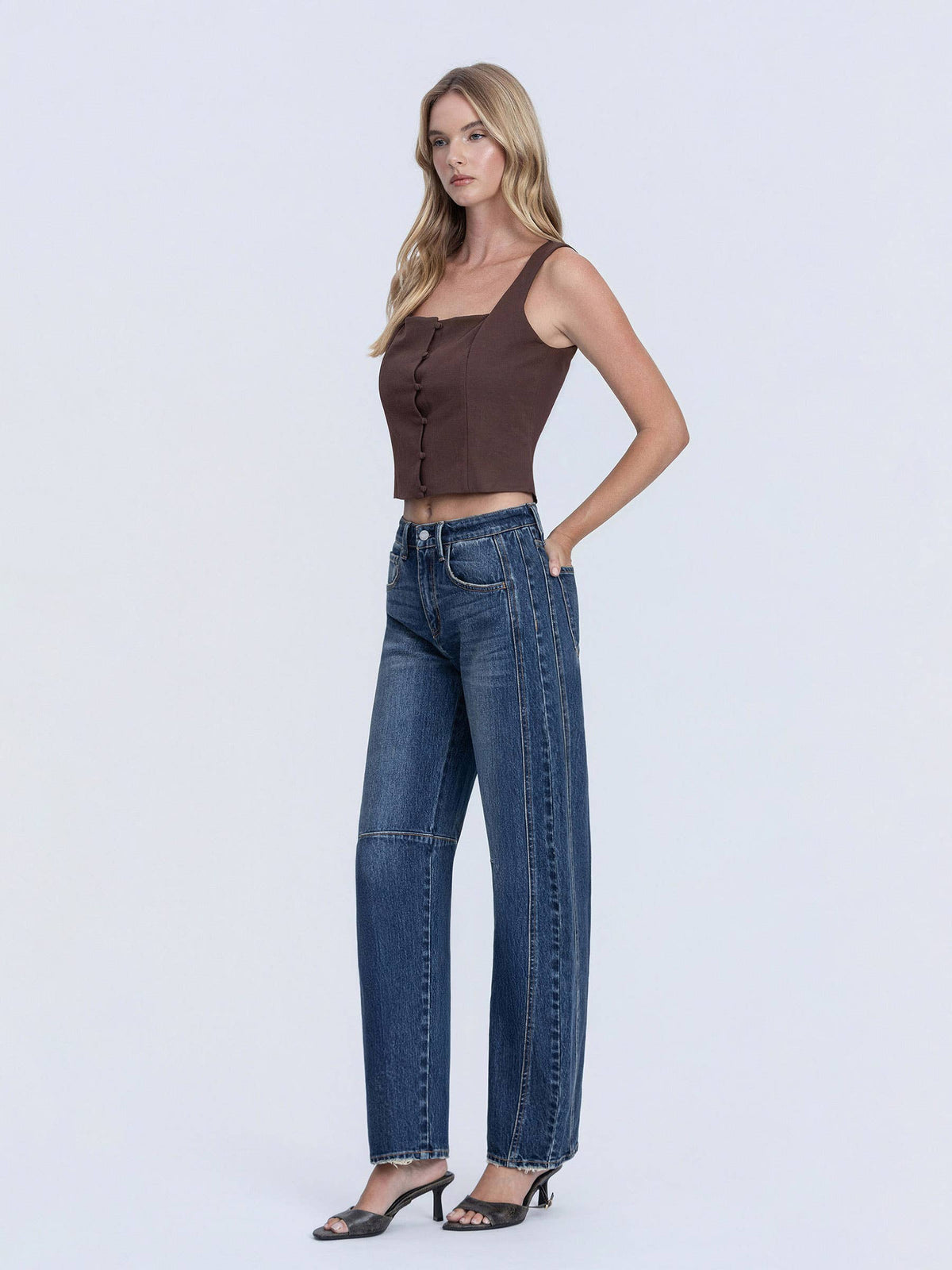 Woman wearing a brown top and blue jeans on a white background