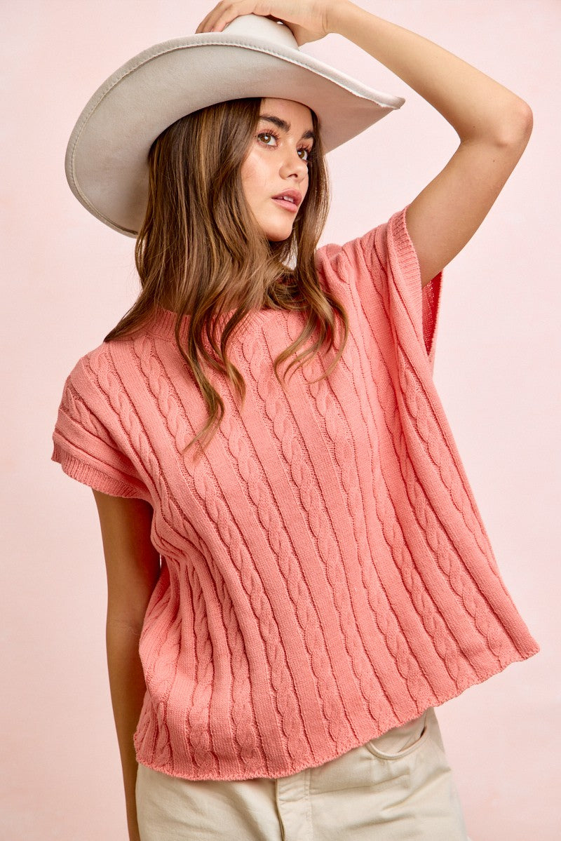 Woman wearing a pink textured top and white hat against a pink background