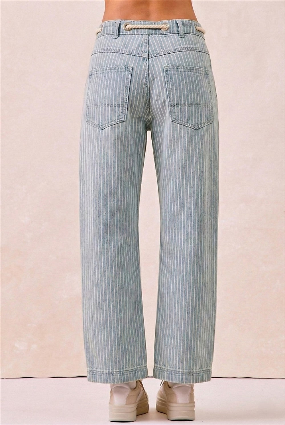 Light blue striped jeans worn by a person on a beige background