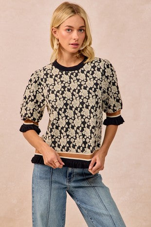 Woman wearing a floral patterned top and jeans on a beige background