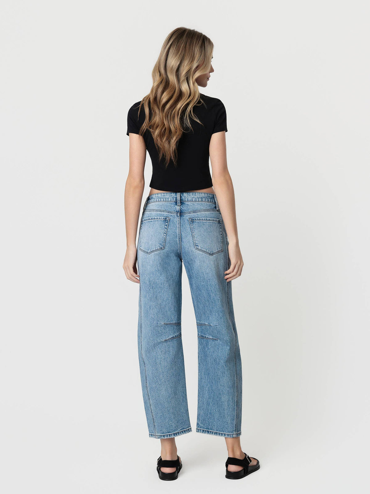 Woman wearing a black top and light blue jeans on a white background