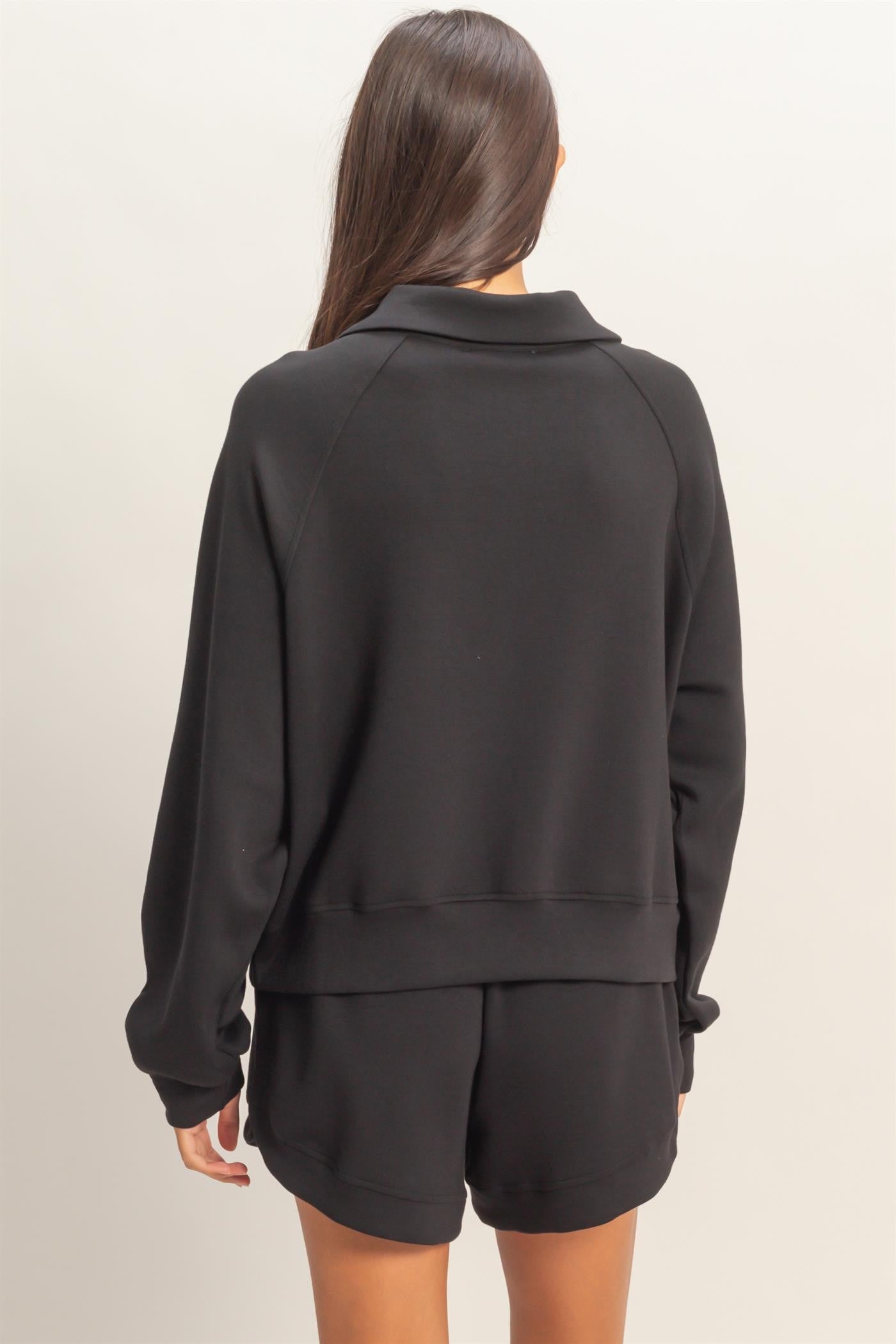 Woman wearing a black tracksuit against a plain background