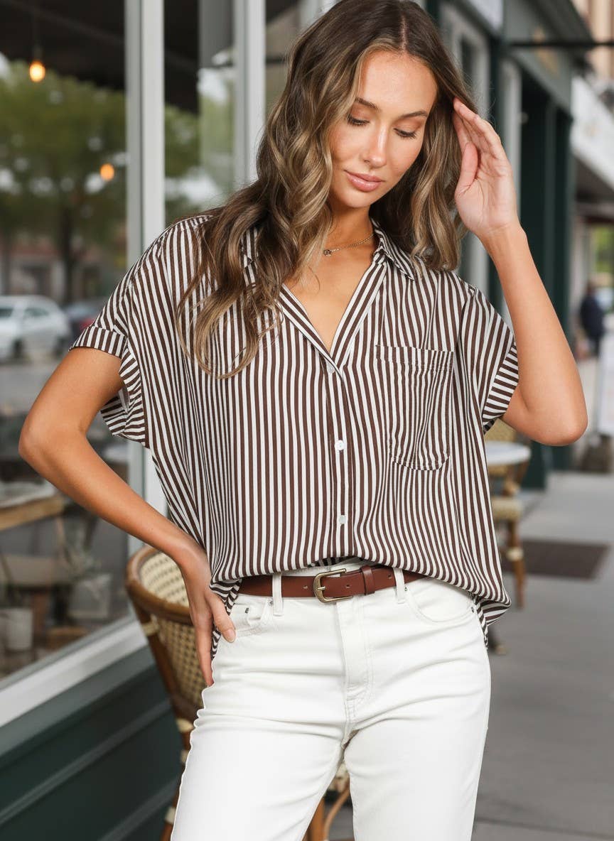 Woman wearing a striped shirt and white pants on a city street.
