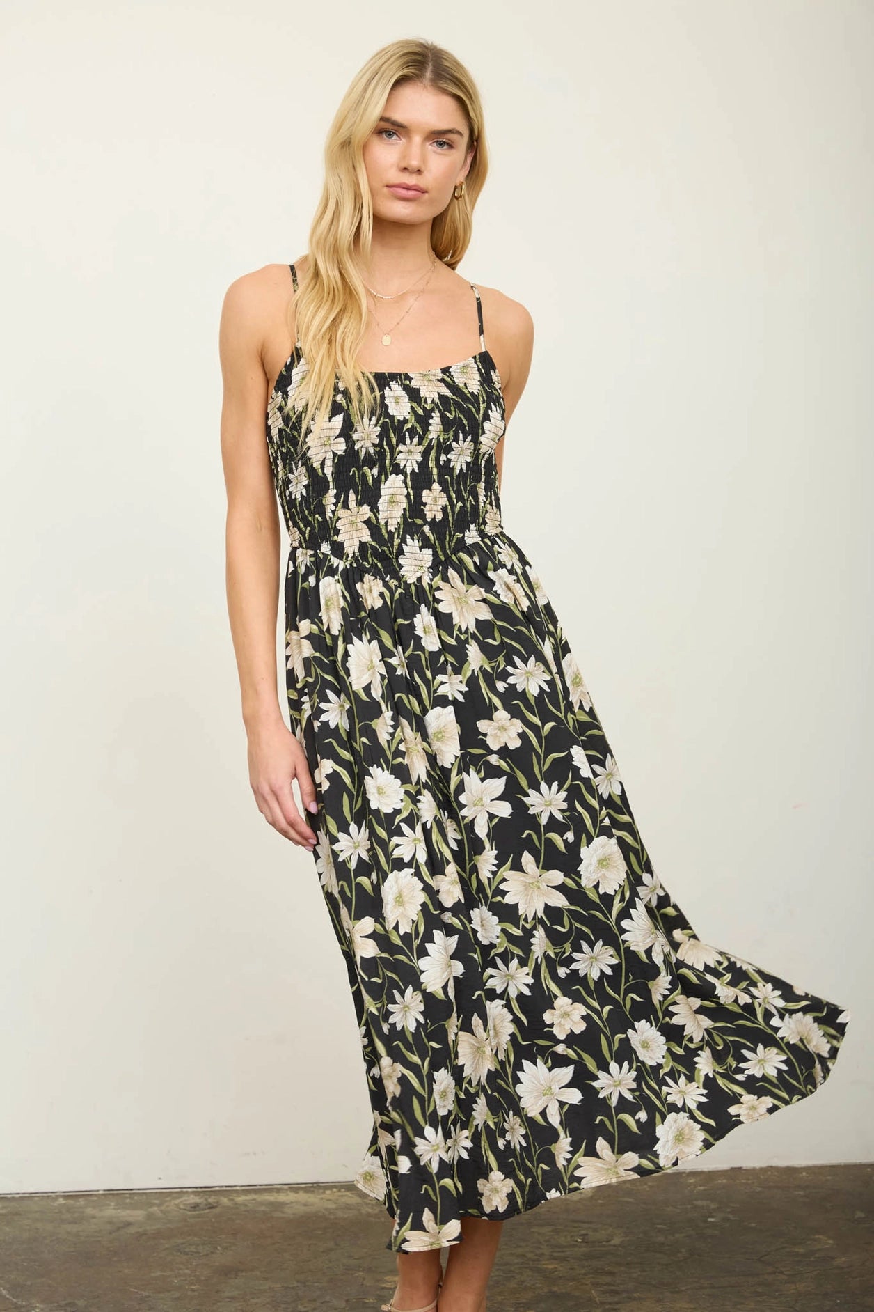 women in black floral dress against white wall