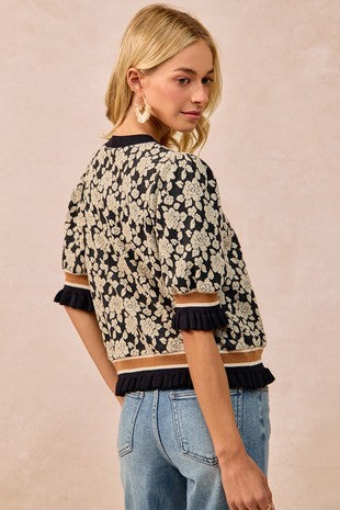 Woman wearing a floral patterned top with ruffled details on a beige background