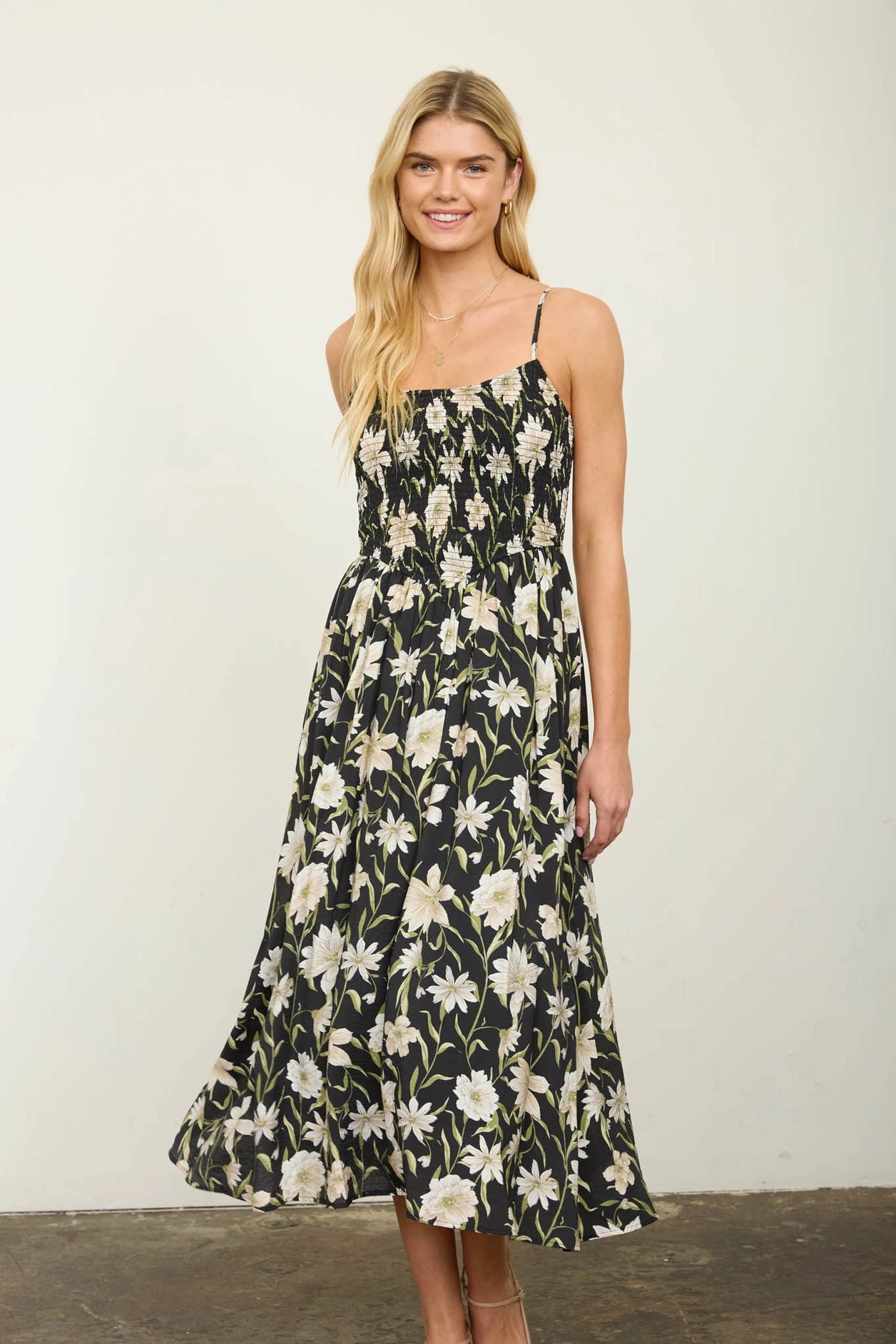 women in black floral dress against white wall