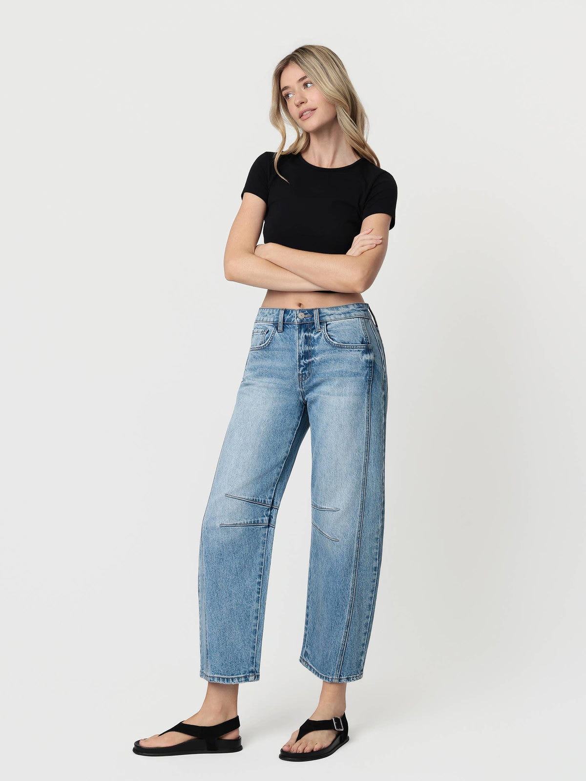 Woman wearing blue jeans and a black top on a white background