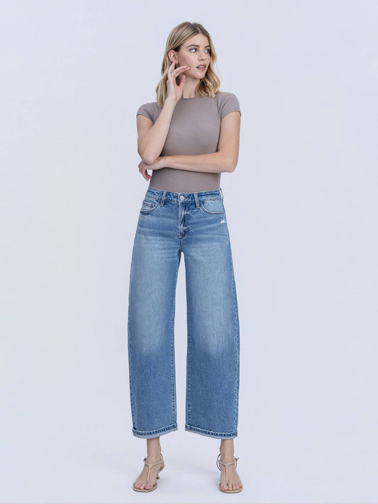 Woman wearing a gray top and blue jeans on a white background