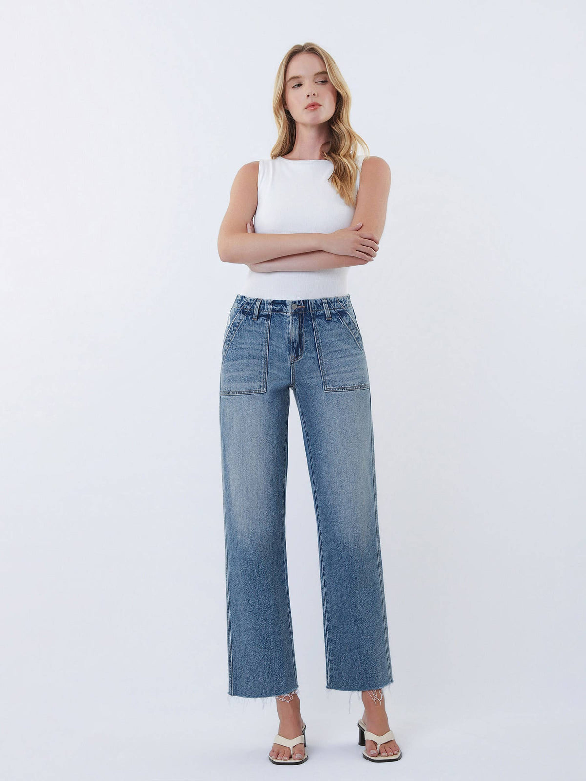 Woman wearing a white top and blue jeans on a white background
