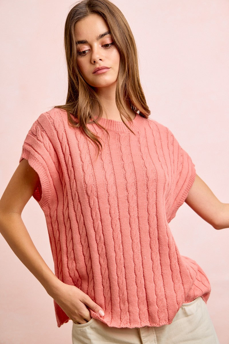 Woman wearing a pink ribbed sweater against a pink background