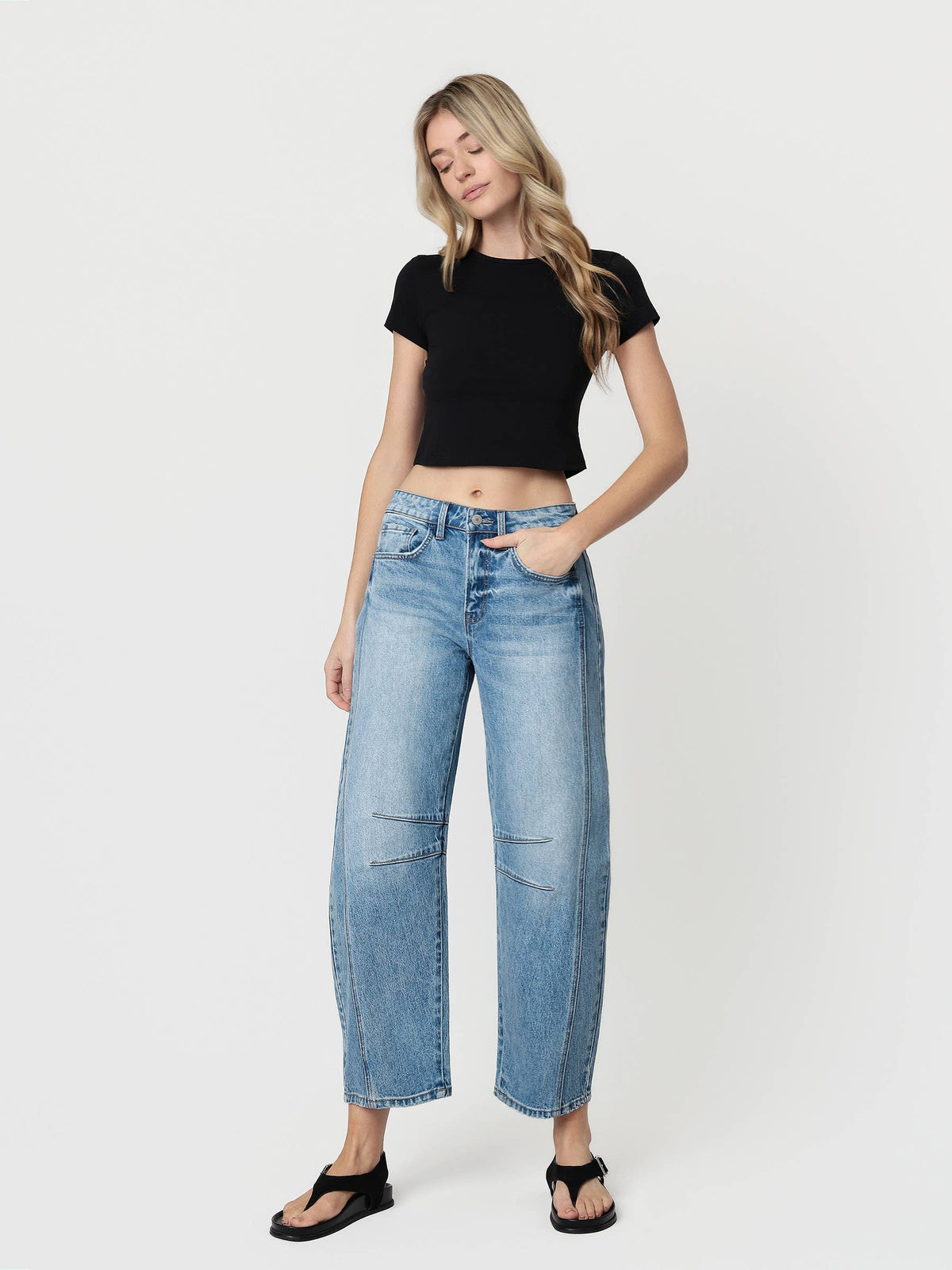 Woman wearing a black t-shirt and blue jeans on a white background