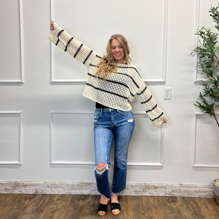 Woman wearing a striped sweater and jeans standing in a room with white paneled walls.