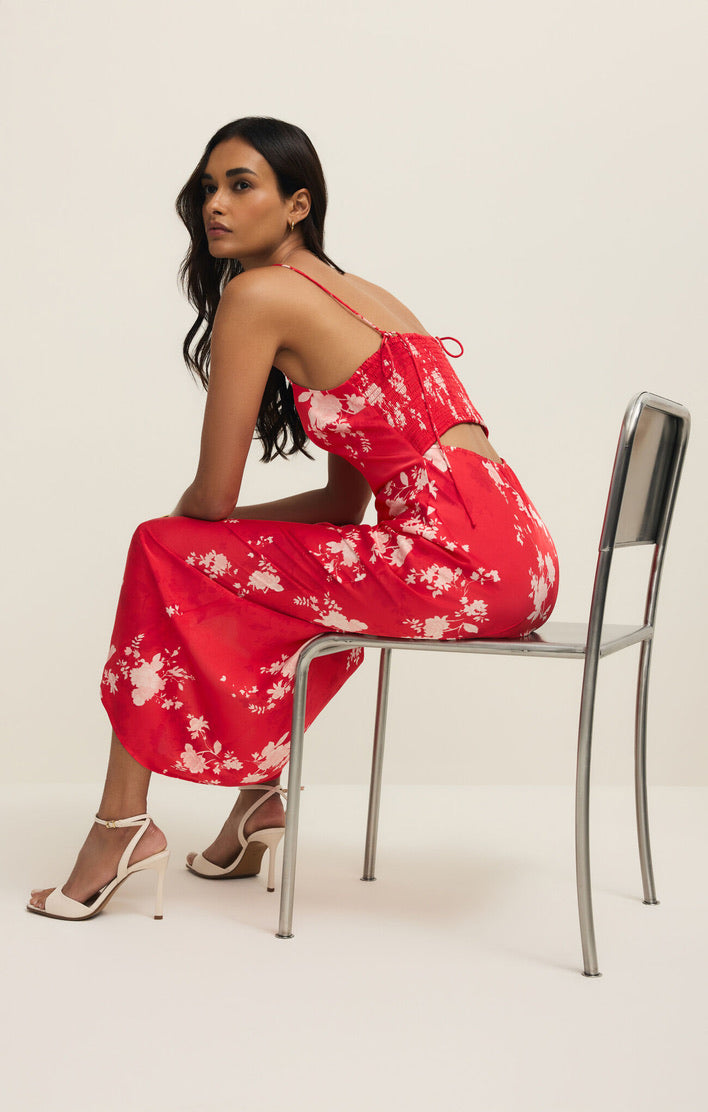 Woman in a red floral dress sitting on a chair against a white background