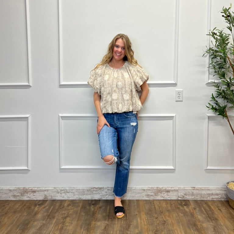 Woman standing in a room with white paneled walls and a plant.