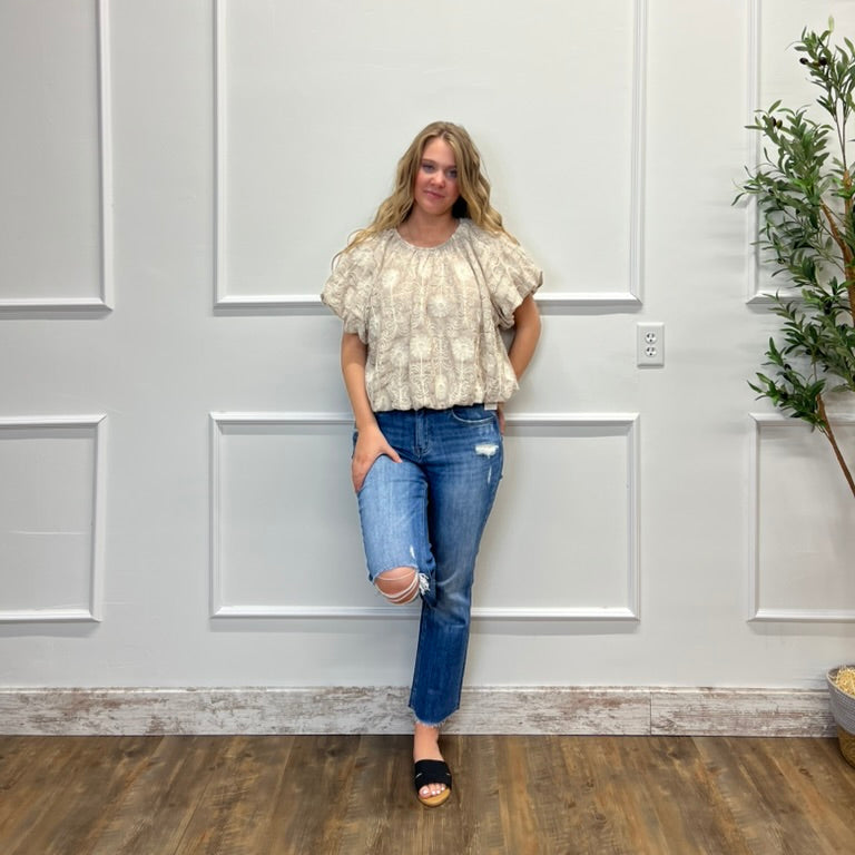 Woman standing in a room with white paneled walls and a plant.