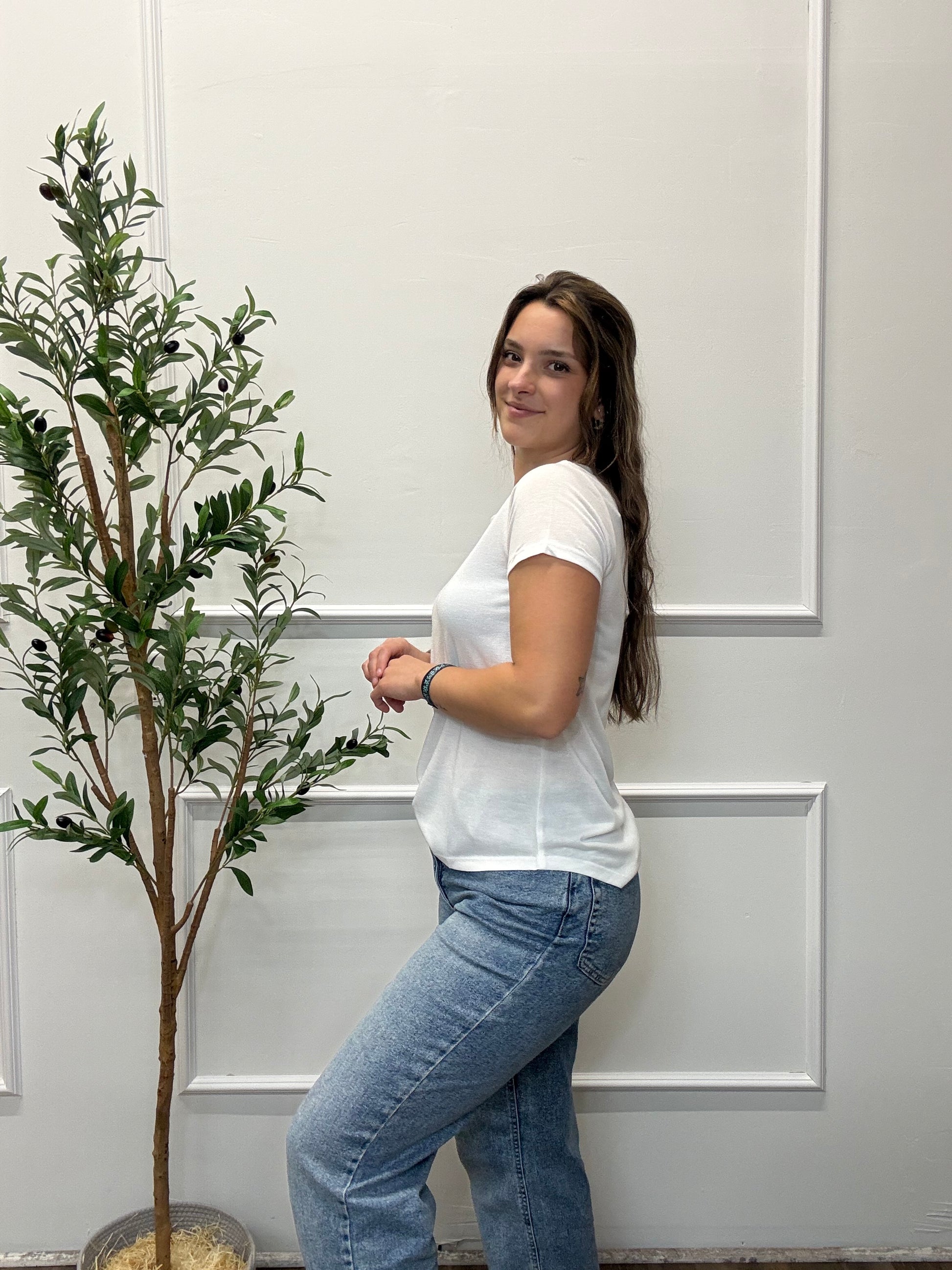 Person lying on a white floor with a plant in the background