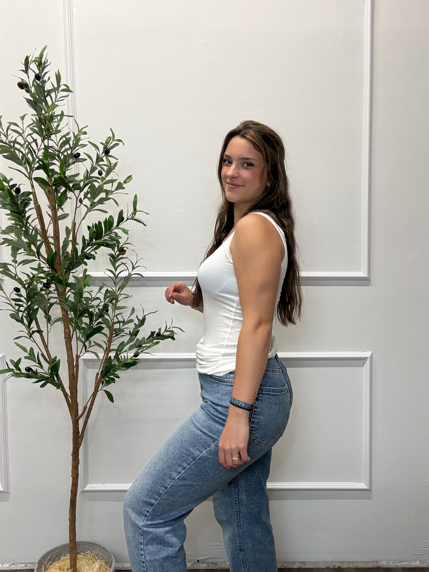 Person lying on a white floor with a plant in the background