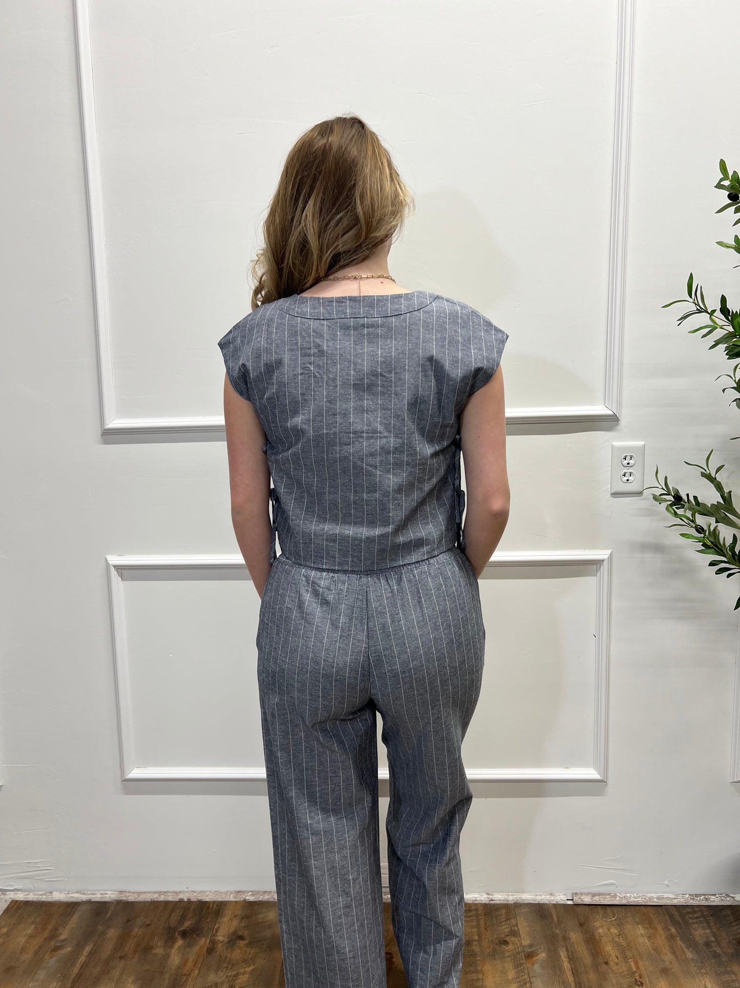 Person wearing a blue denim outfit standing in front of a white door.